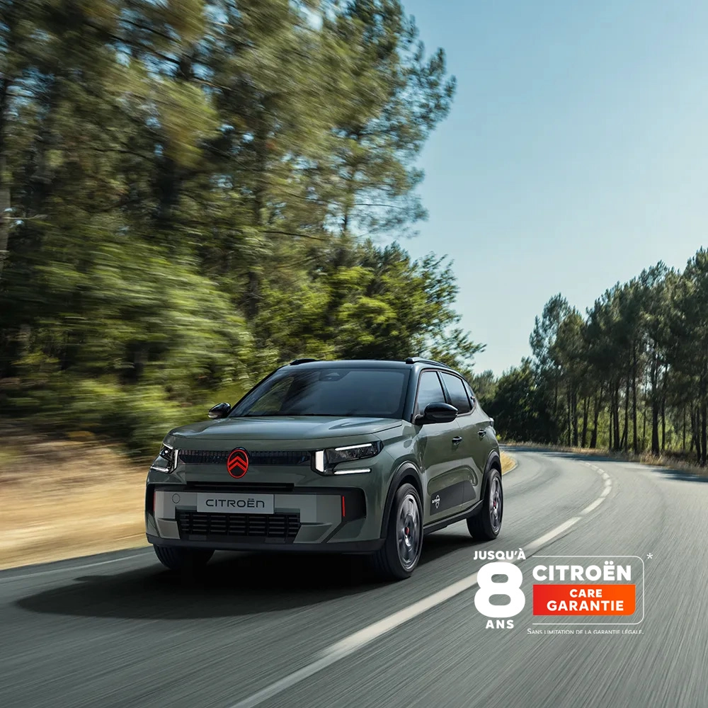 Vue avant trois-quarts de Citroën ë-C3 Outdoor avec signature lumineuse LED, mettant en valeur Citroën Advanced Comfort sur une route panoramique