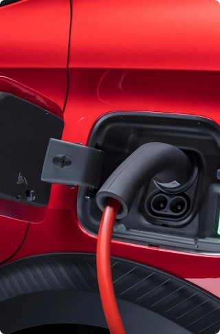 Vue rapprochée de la trappe de recharge de la Citroën ë-C3 Van connectée à un câble, illustrant la mobilité électrique et la simplicité de recharge.
