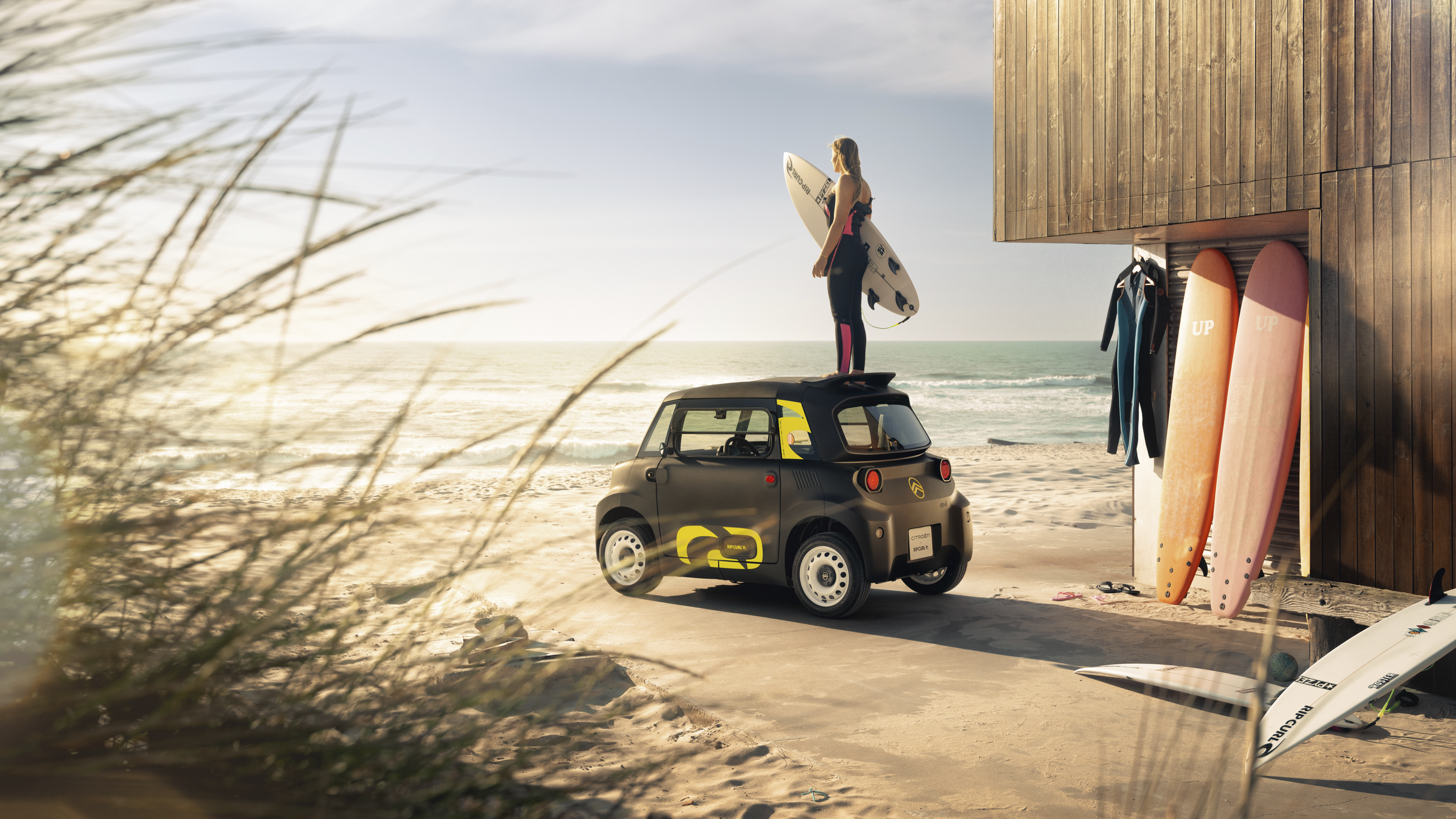Vue arrière lifestyle à la plage de la Citroën Ami x Rip Curl électrique sans permis, Citroën Ami synonyme de liberté surf pour une voiture électrique urbaine