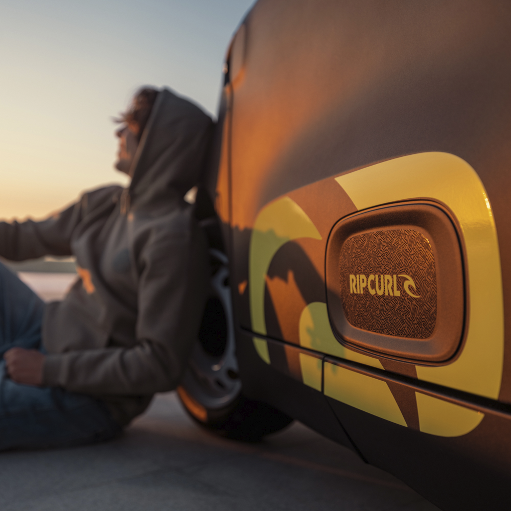 Gros plan sur le badge latéral de la Citroën Ami x Rip Curl électrique sans permis, signature Rip Curl de la Citroën Ami pour une voiture électrique urbaine