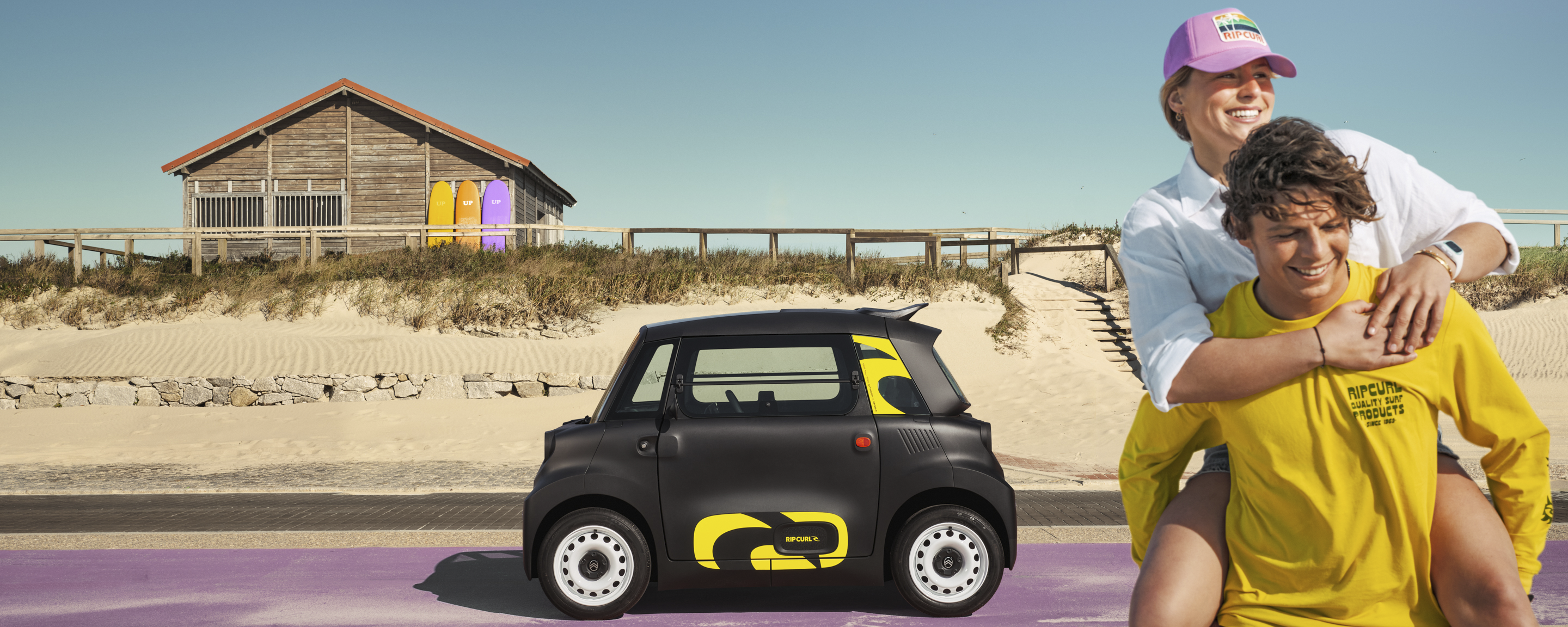 Vue lifestyle latérale de la Citroën Ami x Rip Curl électrique sans permis, Citroën Ami synonyme de liberté en bord de mer pour une voiture électrique urbaine