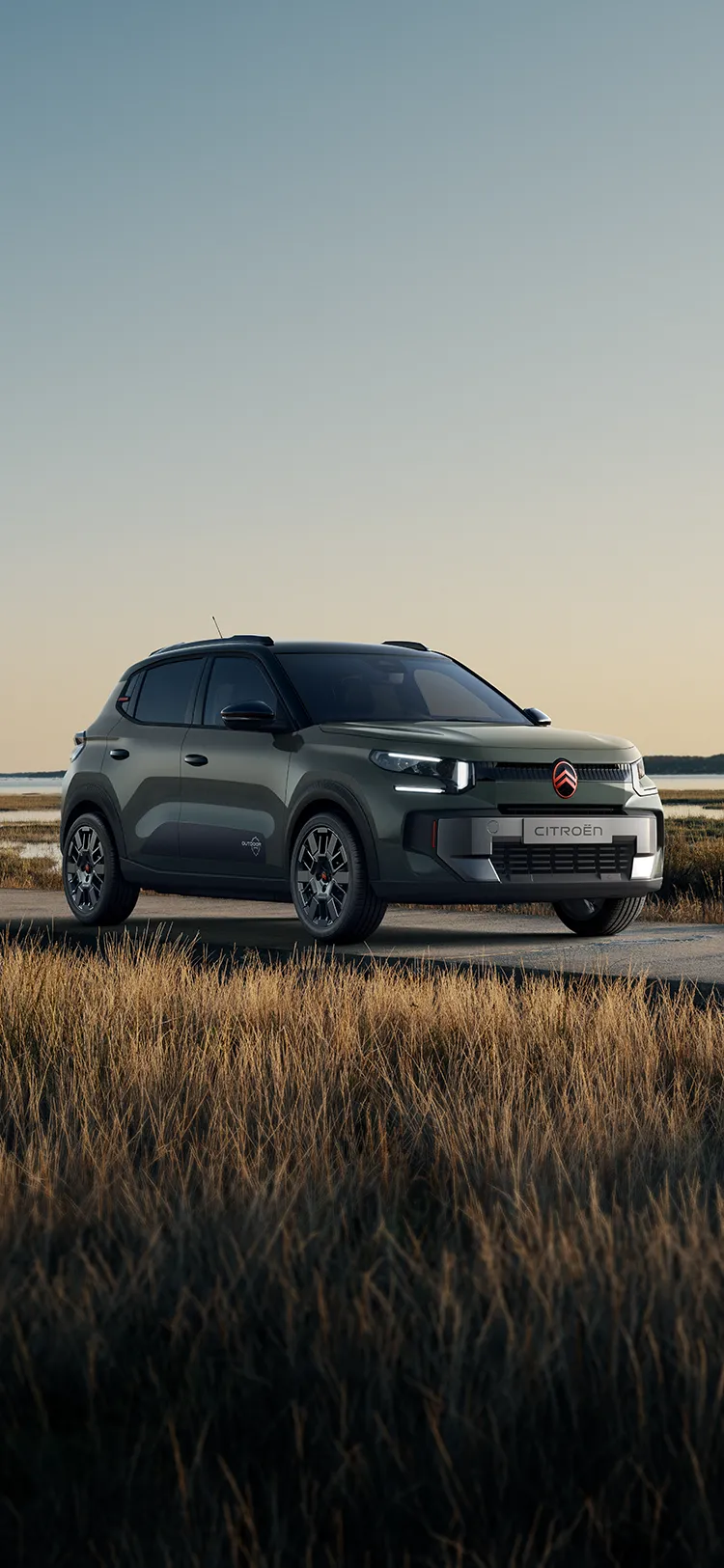 Vue avant trois-quarts de Citroën ë-C3 Outdoor avec signature lumineuse LED, présentant un SUV Advanced Comfort à proximité de zones humides côtières