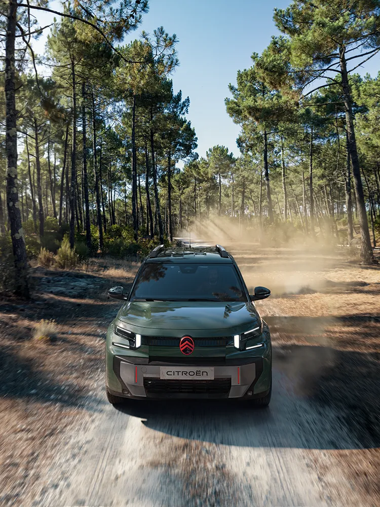 Vue avant aérienne de Citroën C3 Aircross, présentant la signature lumineuse LED et Advanced Comfort d’un SUV familial sur un chemin forestier