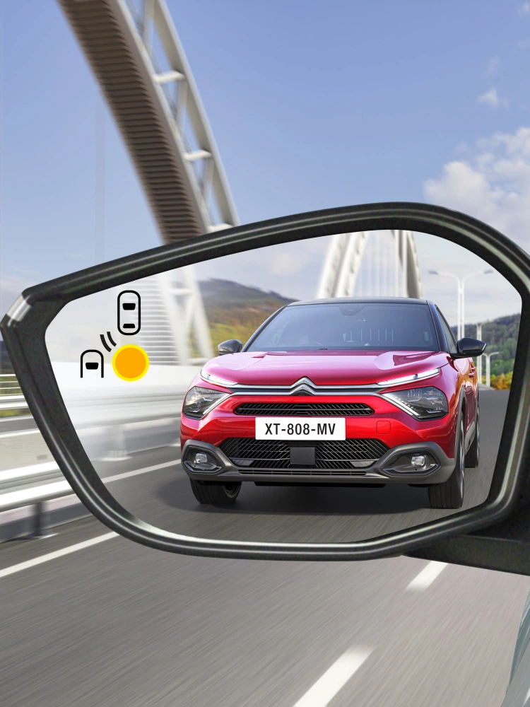 Alerte de détection d’angle mort dans le rétroviseur de la Citroën ë-C4 X montrant un voiture approchant par derrière