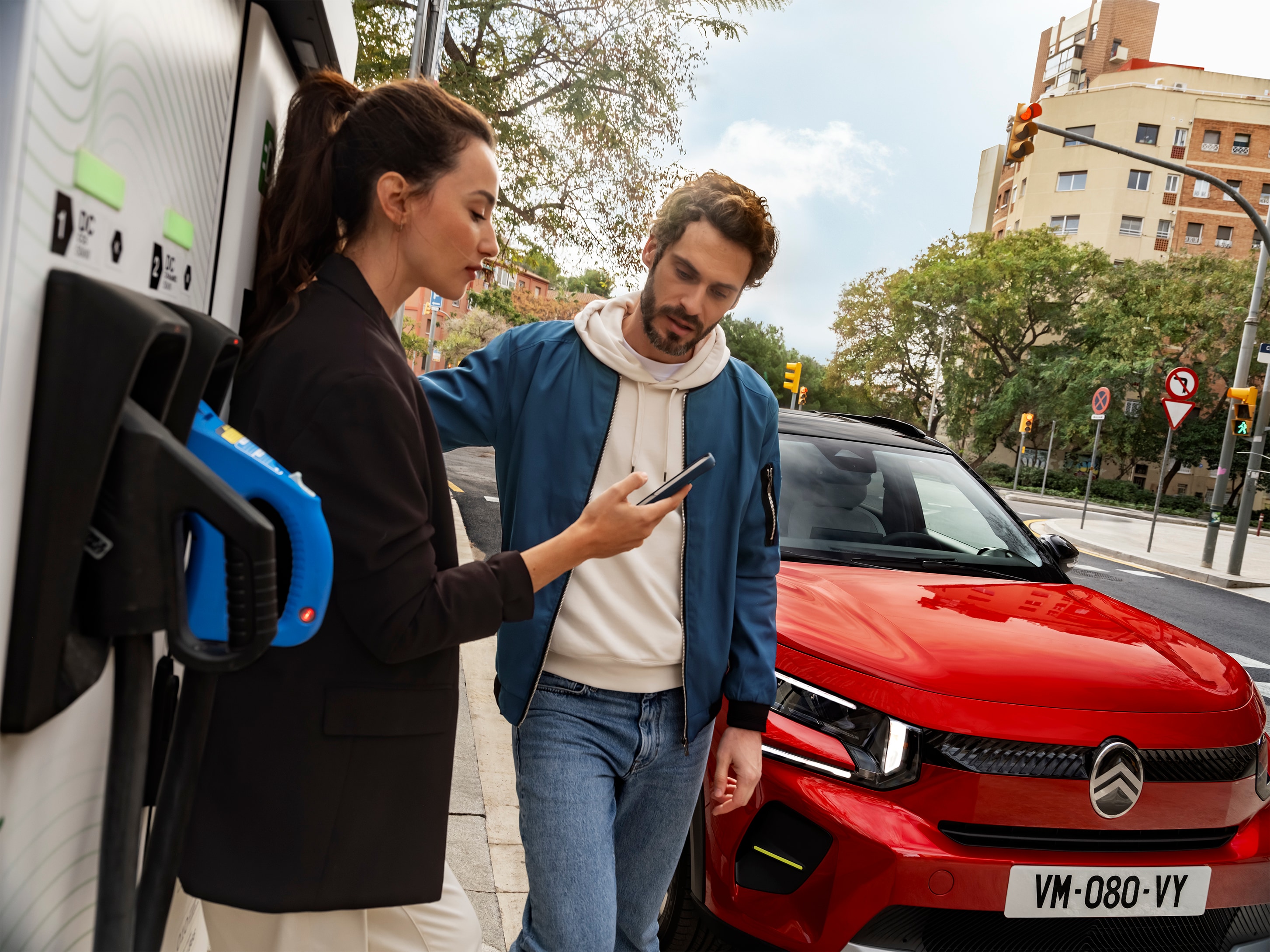 Vue de recharge urbaine du SUV électrique Citroën ë-C3 avec des personnes préparant une recharge rapide pour une mobilité urbaine pratique, efficace et abordable.