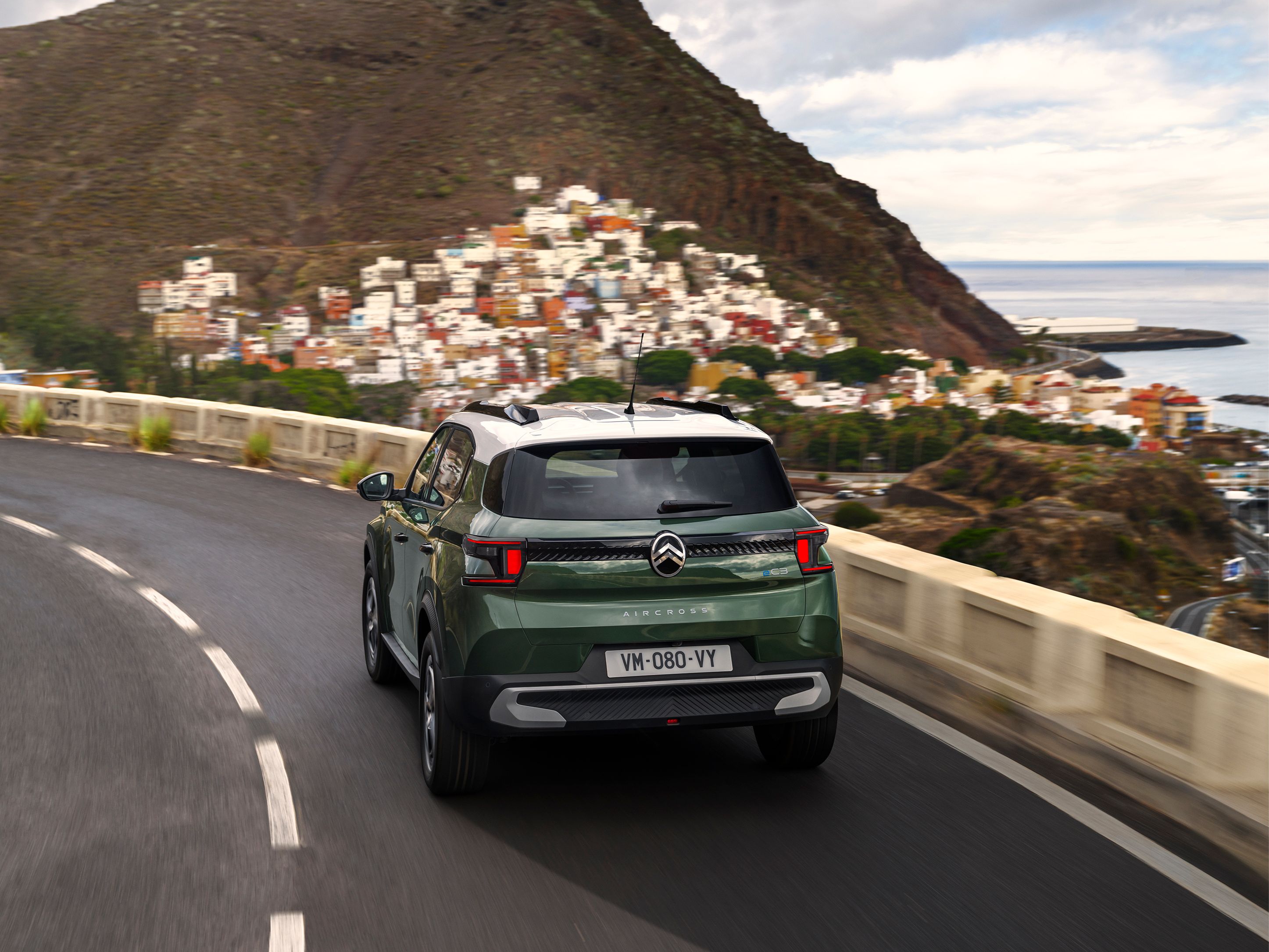 Vue arrière trois quarts du SUV Citroën C3 Aircross sur une route côtière pour une mobilité quotidienne confiante, fluide et abordable.