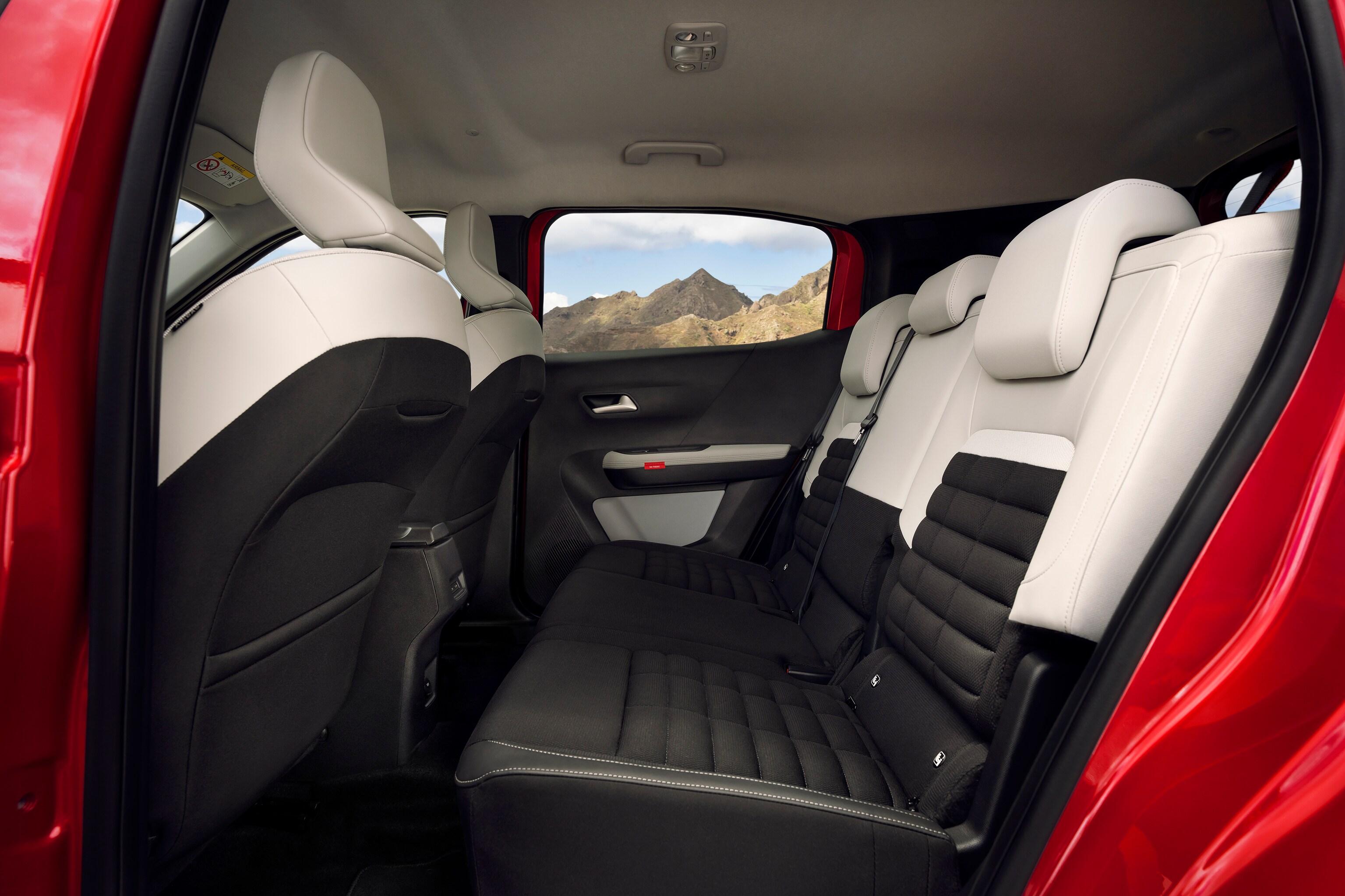 Les sièges arrière passager du SUV compact Citroën sont montrés avec une sellerie noire et blanche et une vue sur la montagne à l’extérieur