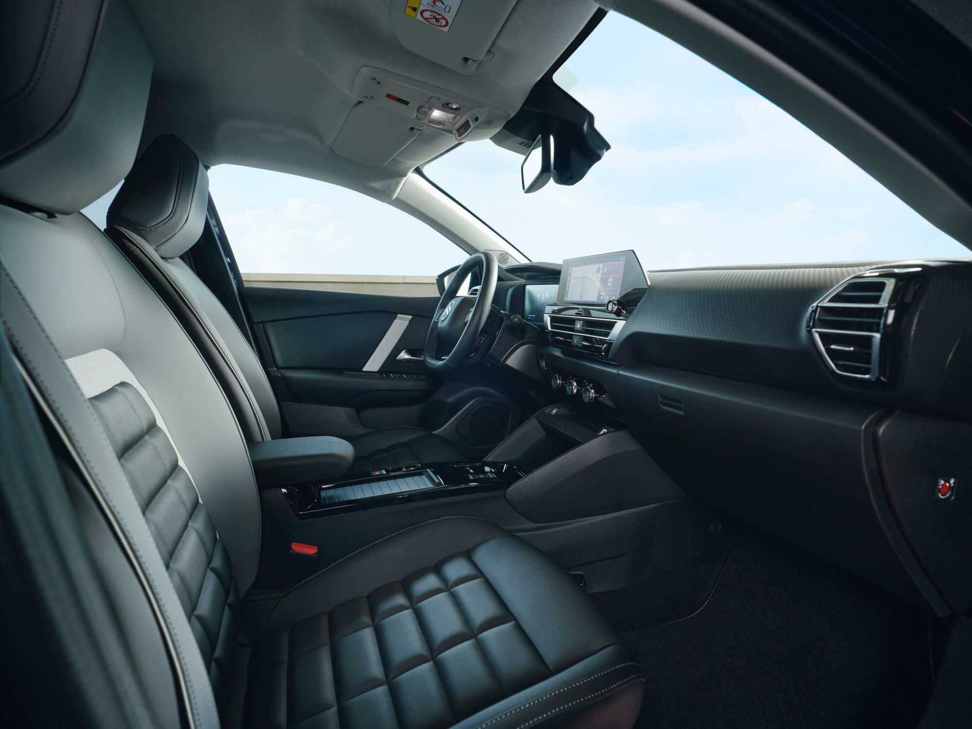 Vue intérieure avant de la Citroën ë-C4 X montrant les sièges, le tableau de bord et l’écran central