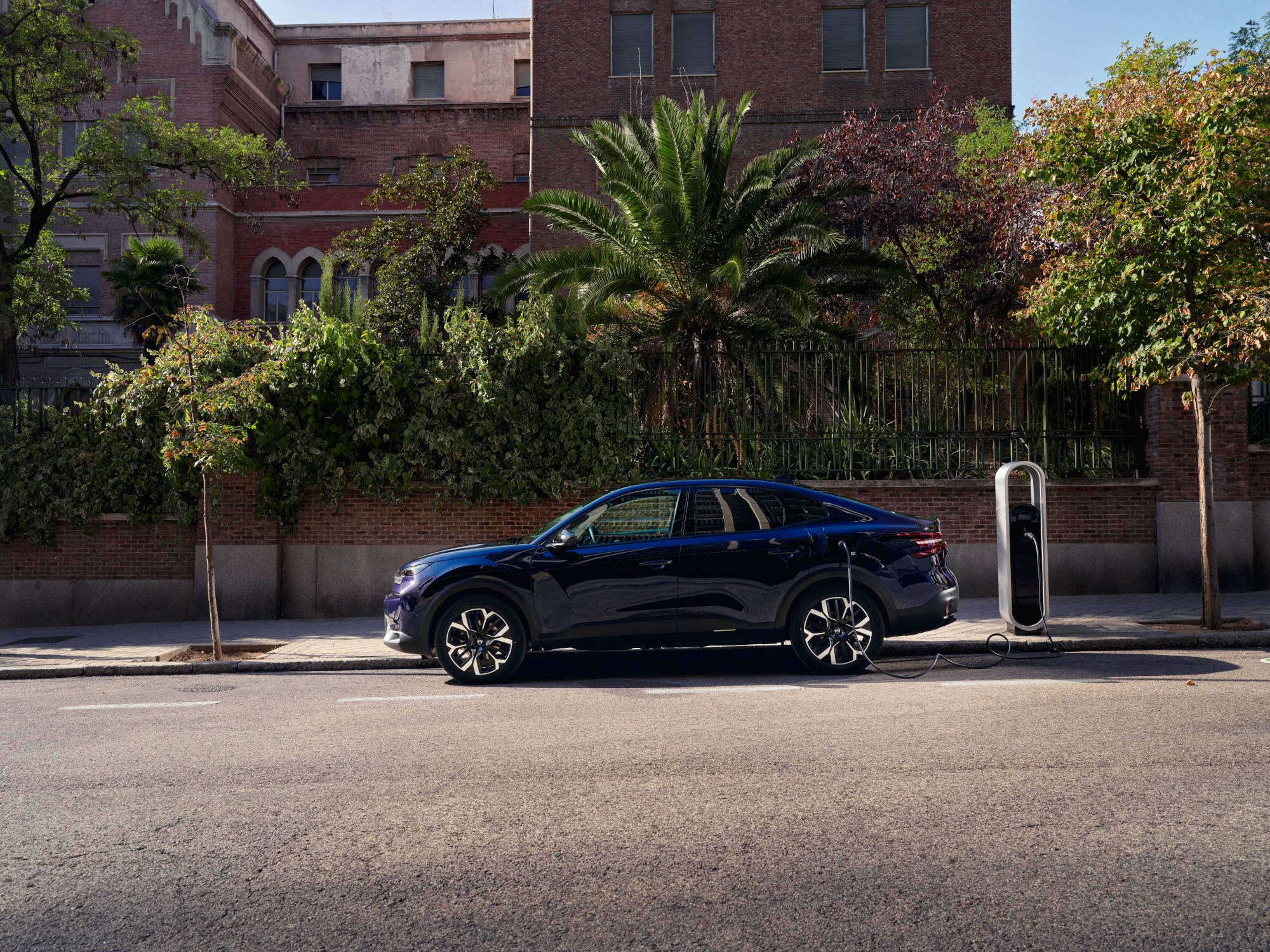 Vue de côté de la recharge électrique fastback Citroën ë-C4 X dans la rue, mettant en avant une mobilité urbaine pratique et abordable